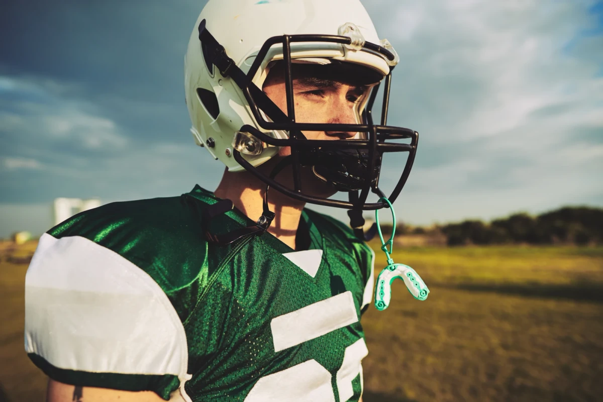 Football player with a sports mouthguard attached to his helmet