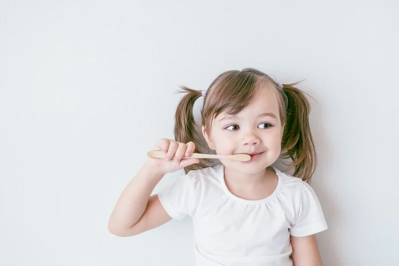 A young child brushing her teeth