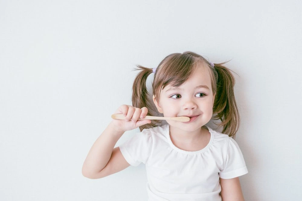 A young child brushing her teeth